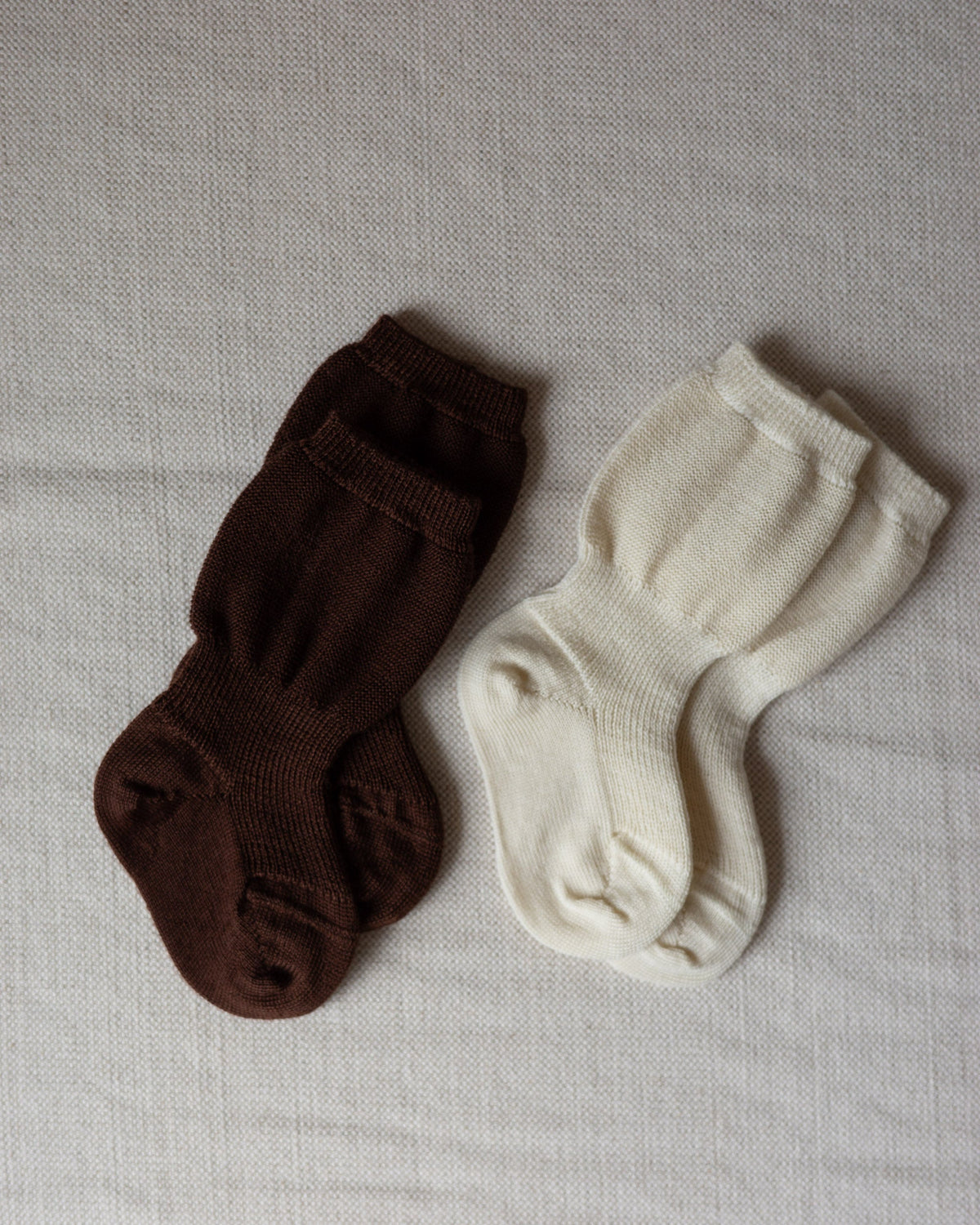 Varig organic wool baby socks in brown and off-white with ribbed cuffs for a secure fit on a neutral fabric background