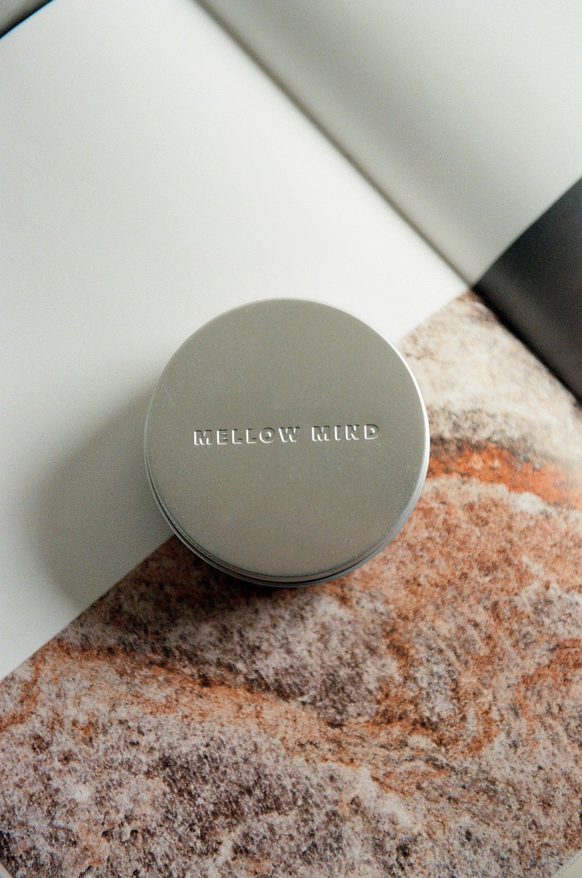 Mellow Mind reiseboks i aluminium med preget logo, på teksturert overflate
